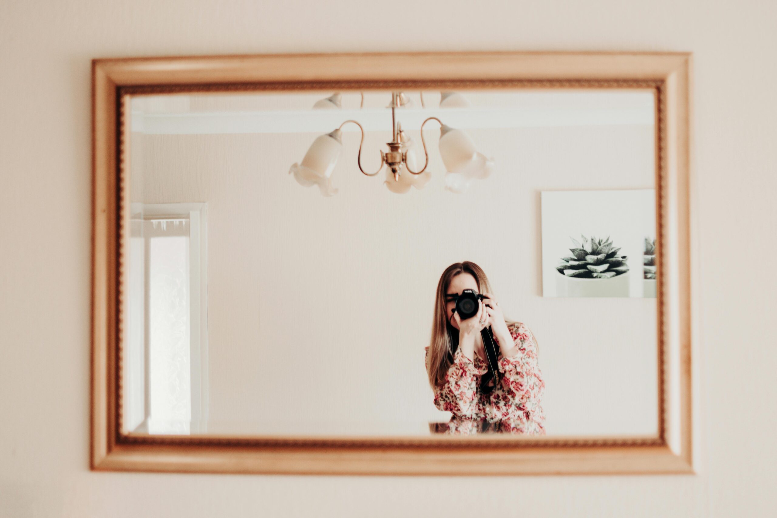 A woman photographer taking a picture in a beautifully framed mirror.