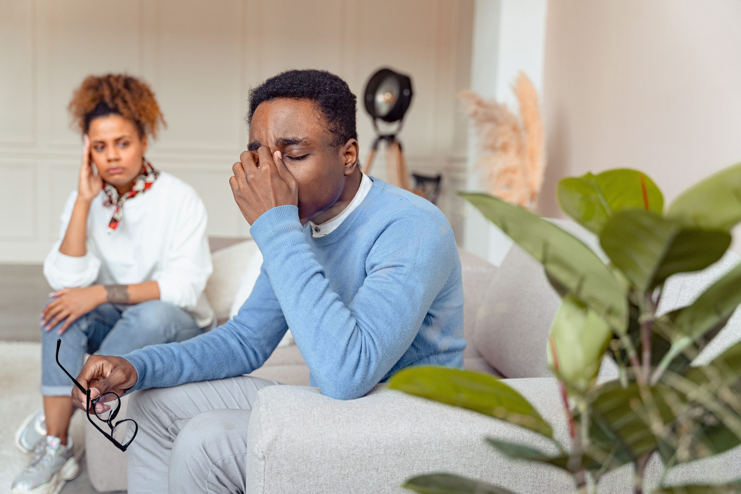 Man in blue sweater looking distressed during a therapy session indoors.